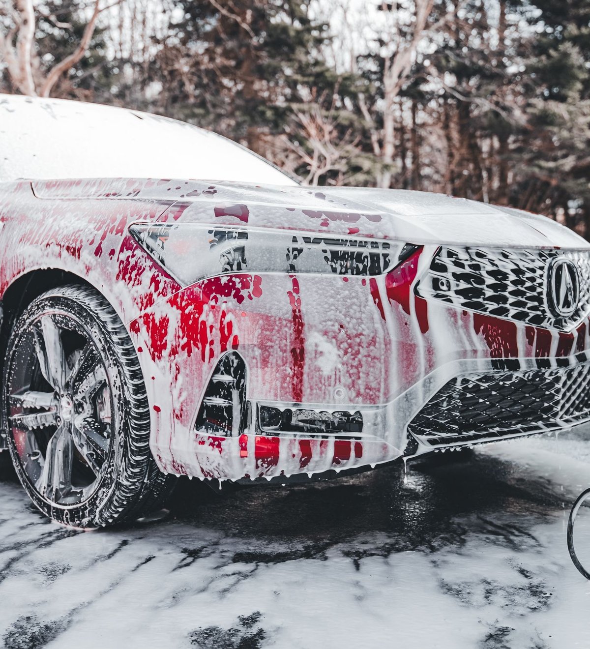 Sedan covered in thick foam during a hand-wash foam cannon rinse