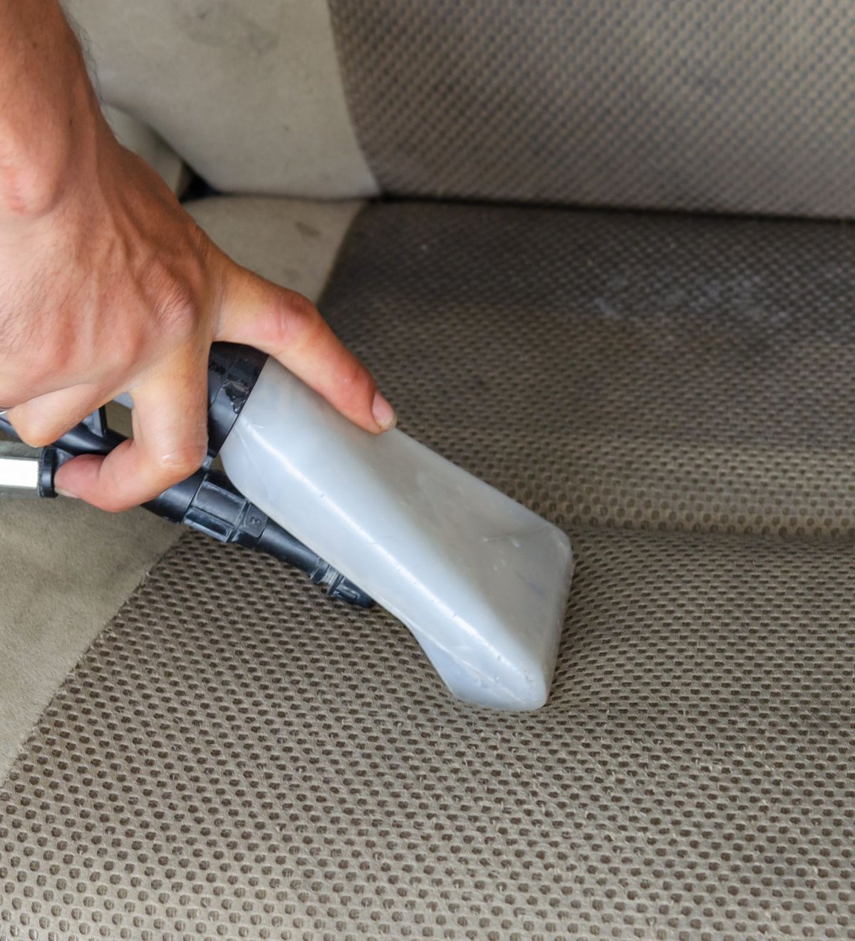 Vacuum nozzle deep cleaning a car seat and dashboard interior